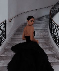 a woman in a black dress sitting on some stairs