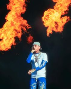 a man standing on top of a stage with fire behind him