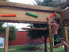 a young boy climbing on top of a wooden structure with two orange and green toys