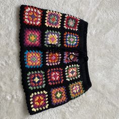 a crocheted granny blanket is laying on a white carpet and it looks like something out of an old book