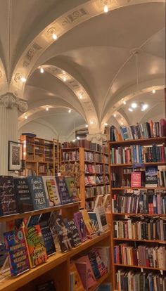 the inside of a bookstore with many books on shelves and lights hanging from the ceiling