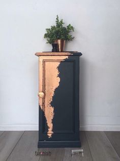 a black and gold cabinet with a potted plant sitting on it's top