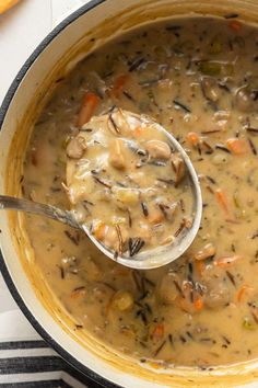 a ladle full of mushroom soup with carrots and celery on the side