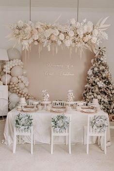 a table set up for a christmas party with white balloons and decorations on the wall