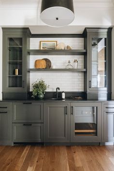 a kitchen with gray cabinets and wooden floors