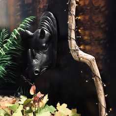 a rhino head mounted to the side of a wall next to green plants and lights