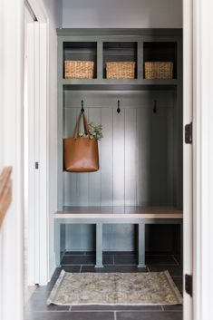 an entryway with a bench and baskets on the wall, along with a rug