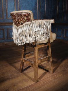 an old wooden chair with fringed fabric on it's back and foot rest