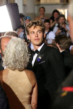 a young man in a tuxedo standing next to an older woman with grey hair