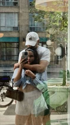 a man and woman taking a selfie in front of a building with a bicycle