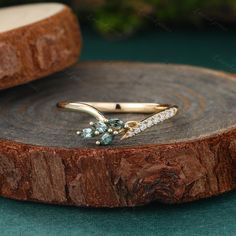 a gold ring with blue and white stones on it sitting on top of a piece of wood