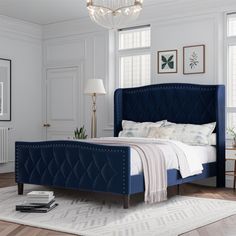 a bedroom with white walls and wooden floors, a blue bed frame is flanked by a chandelier that hangs from the ceiling