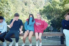 four young people sitting on a park bench