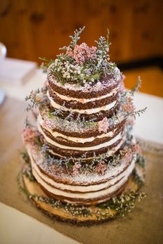 a multi layer cake with frosting and flowers on the top is sitting on a table