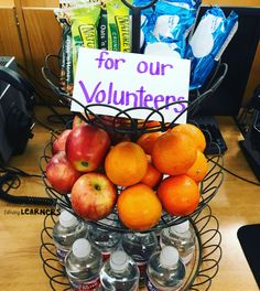 a basket filled with oranges and apples on top of a wooden table next to water bottles