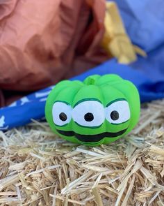 a green apple with googly eyes sitting on hay