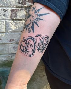 a person with a tattoo on their arm that has two cats in heart shaped frames