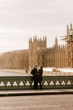 two people standing next to each other in front of the big ben clock tower and houses of parliament