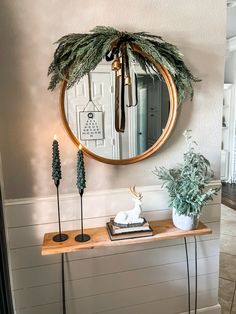 a wooden table topped with a mirror and two potted plants on top of it