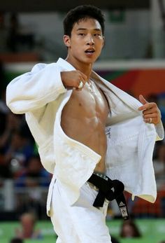 a man with no shirt on standing in front of a crowd holding a white jacket over his shoulder