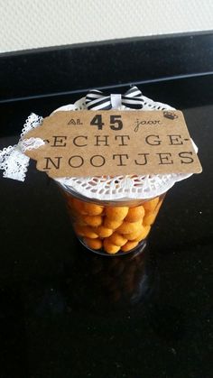 a glass jar filled with lots of cookies on top of a black table next to a white doily