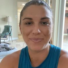 a woman in a blue tank top is smiling for the camera while looking at the camera