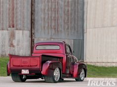 an old red truck parked in front of a building