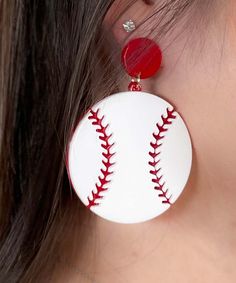 a close up of a person wearing earrings with baseballs on them