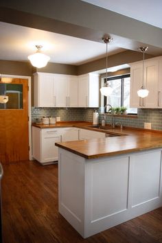 a kitchen with white cabinets and wood floors