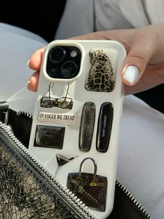 a woman is holding her phone case with many different things on it, including purses and sunglasses