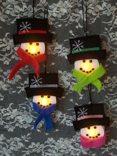 four snowmen wearing hats and scarfs with lights on them