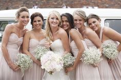 a group of women standing next to each other in front of a white van holding bouquets