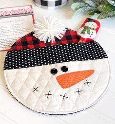 a close up of a snowman ornament on a table with christmas decorations