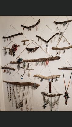 a white wall with many necklaces hanging from it's sides and wooden sticks attached to them