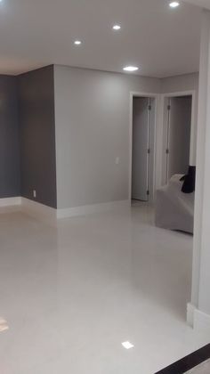 an empty living room with white floors and gray walls, is seen in this image