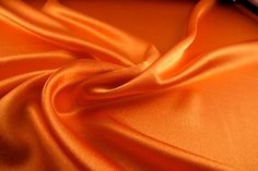 an orange satin fabric that is laying on top of a table with a cell phone next to it