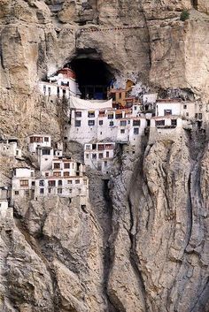 a mountain side with some buildings built into the side of it's cliff face