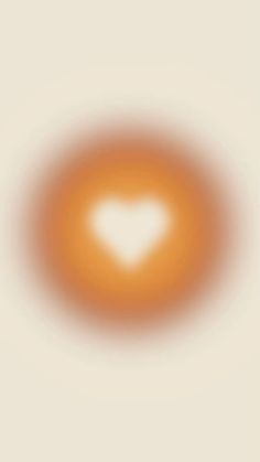 an orange circle with a white heart in the center on a beige background that appears to be blurry