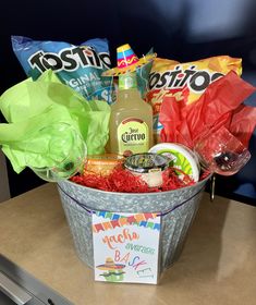 a bucket filled with candy, condiments and snacks