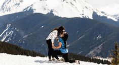 two people standing on top of a snow covered mountain