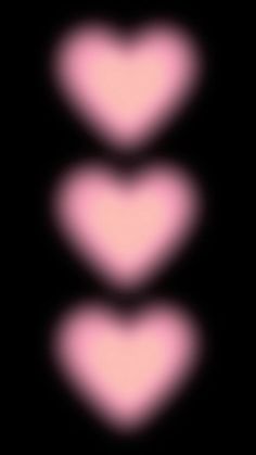 three pink hearts are shown in the middle of a black background with light coming from them