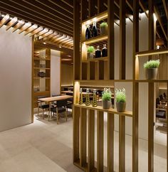 the interior of a restaurant with wooden shelves and plants in vases on the counter