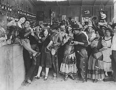 a group of people standing next to each other in front of a wall filled with bottles