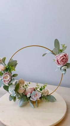 a floral arrangement in a gold hoop on top of a wooden table