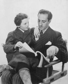 an old black and white photo of two people sitting on a sled