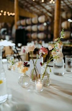 flowers in vases are sitting on the table at this wedding reception with candles and wine glasses