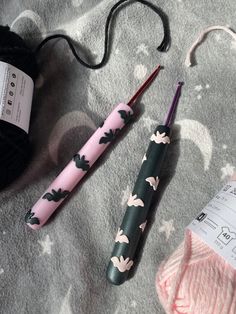 two crochet hooks, yarn and knitting needles laying on a blanket next to each other