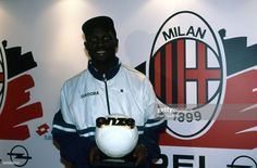 a man holding a soccer ball in front of a wall