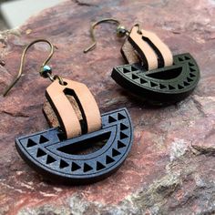 two black and brown earrings sitting on top of a rock