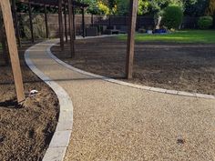 a walkway in the middle of a garden with rocks and gravel around it, leading to a pergolated area